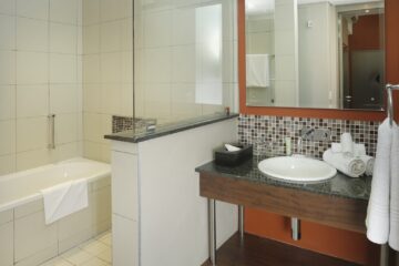 Executive Suite bathroom with soaking tub, walk-in shower and mosaic-tiled vanity at Metcourt Umfolozi, Empangeni