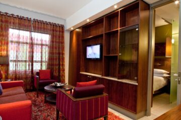 Executive Suite lounge with striped armchairs and view into the bedroom at Metcourt Umfolozi, Empangeni