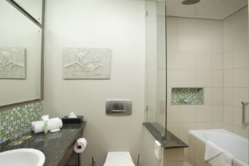 Superior Room bathroom with bathtub, glass shower and mosaic accents at Metcourt Umfolozi, Empangeni